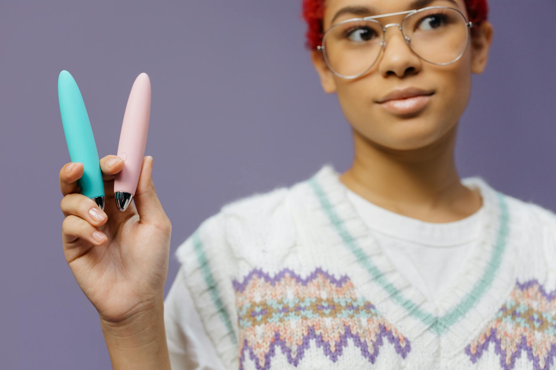 A woman holding colorful vibrators, representing self-pleasure and personal intimacy