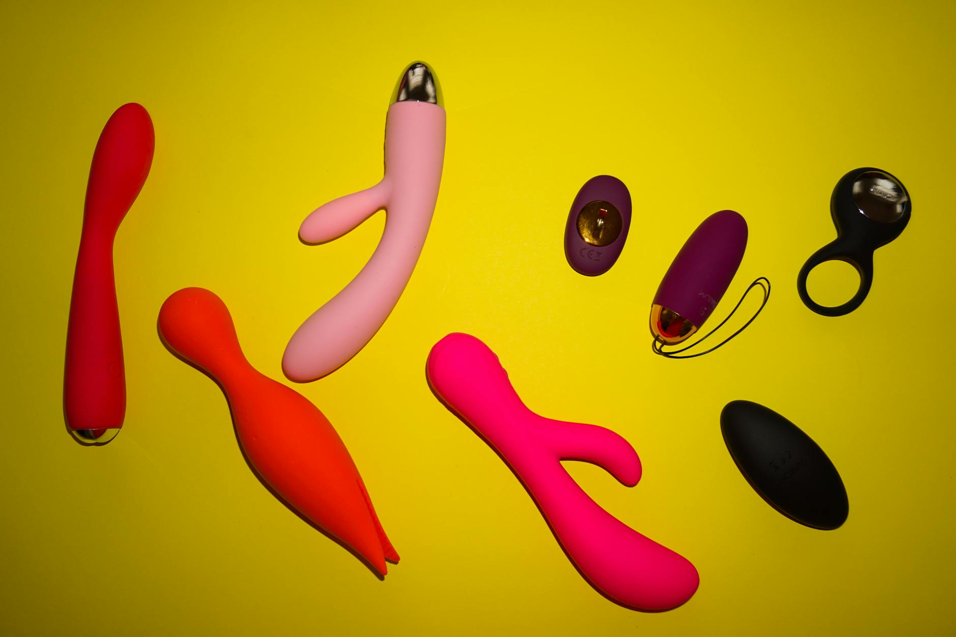 Hand holding a blue silicone clitoral vibrator against purple background