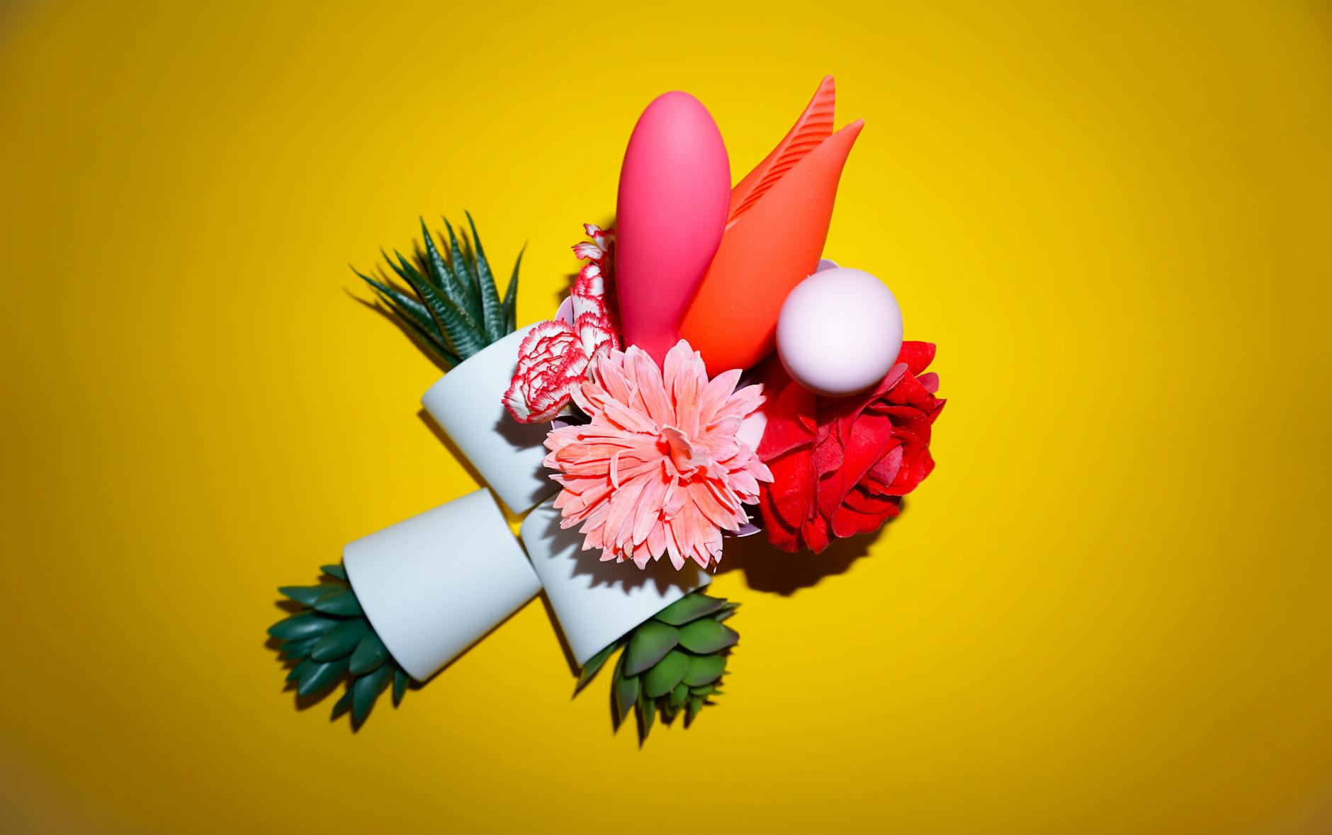 Vibrator mit Blüten in einer Holographic-Geschenktasche auf gelbem Hintergrund, symbolisiert Freude und Partnerschaft